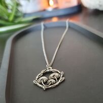 Circular pendant on silver chain depicting 3 mushrooms in a ring of leaves with a textured appearance