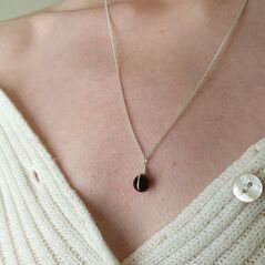 Small black onyx sphere bound in a simple wire wrap onto silver chain
