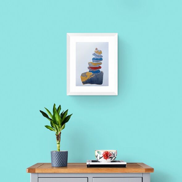 Blue Yellow and Silver Pebbles Stack Print in Framed in White on a Blue Wall Above a Wooden Drawer Unit